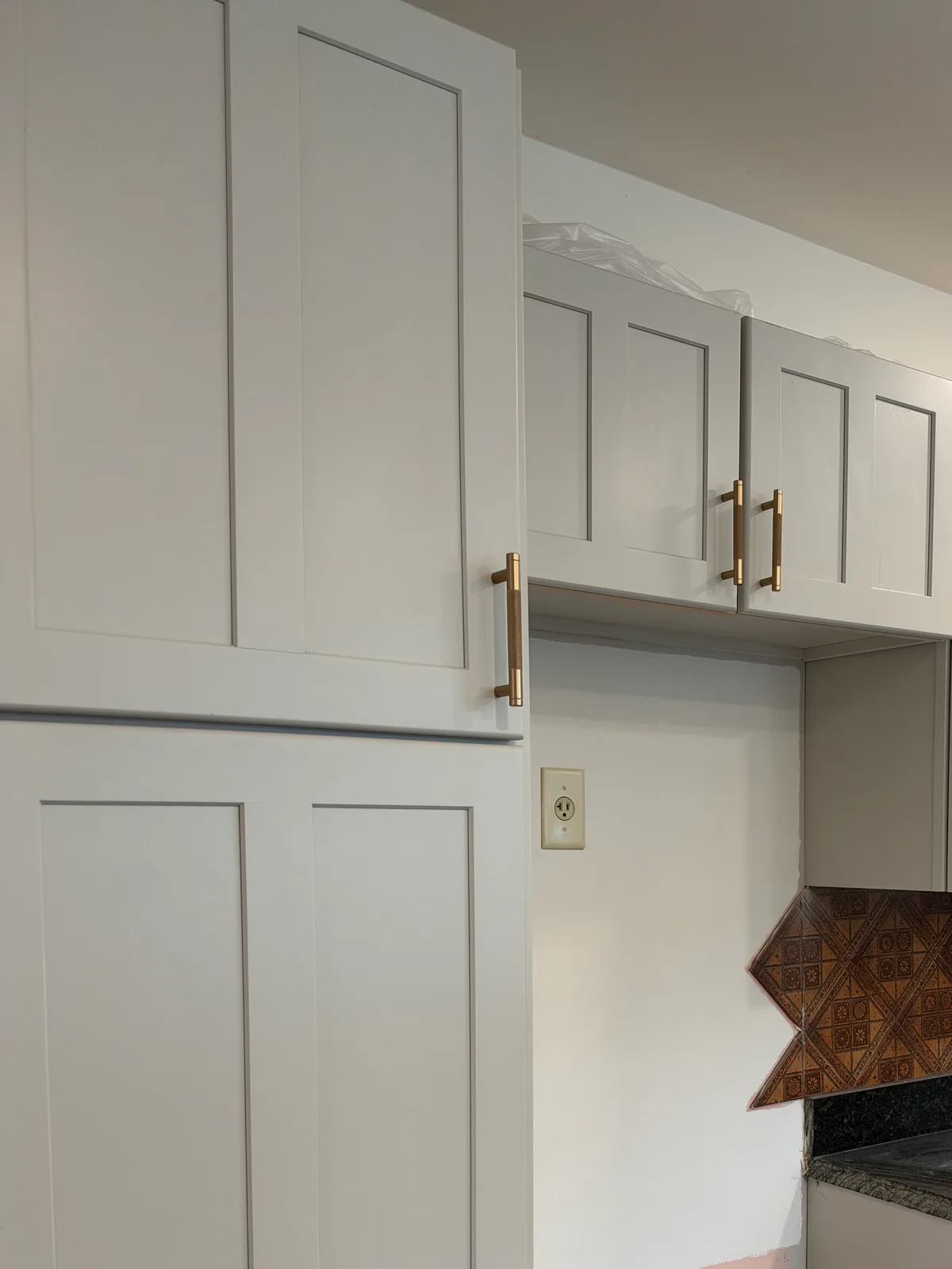 Same kitchen cabinets after refinishing in light gray with gold pulls